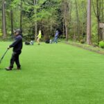 Professional artificial grass installers finishing a backyard lawn installation in the Seattle, Washington area