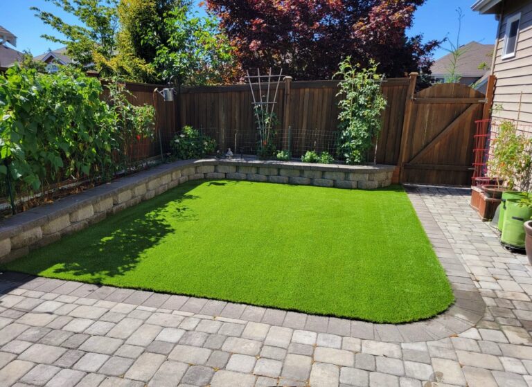 Backyard with synthetic turf and a stone patch wrapped around half of it in a curve